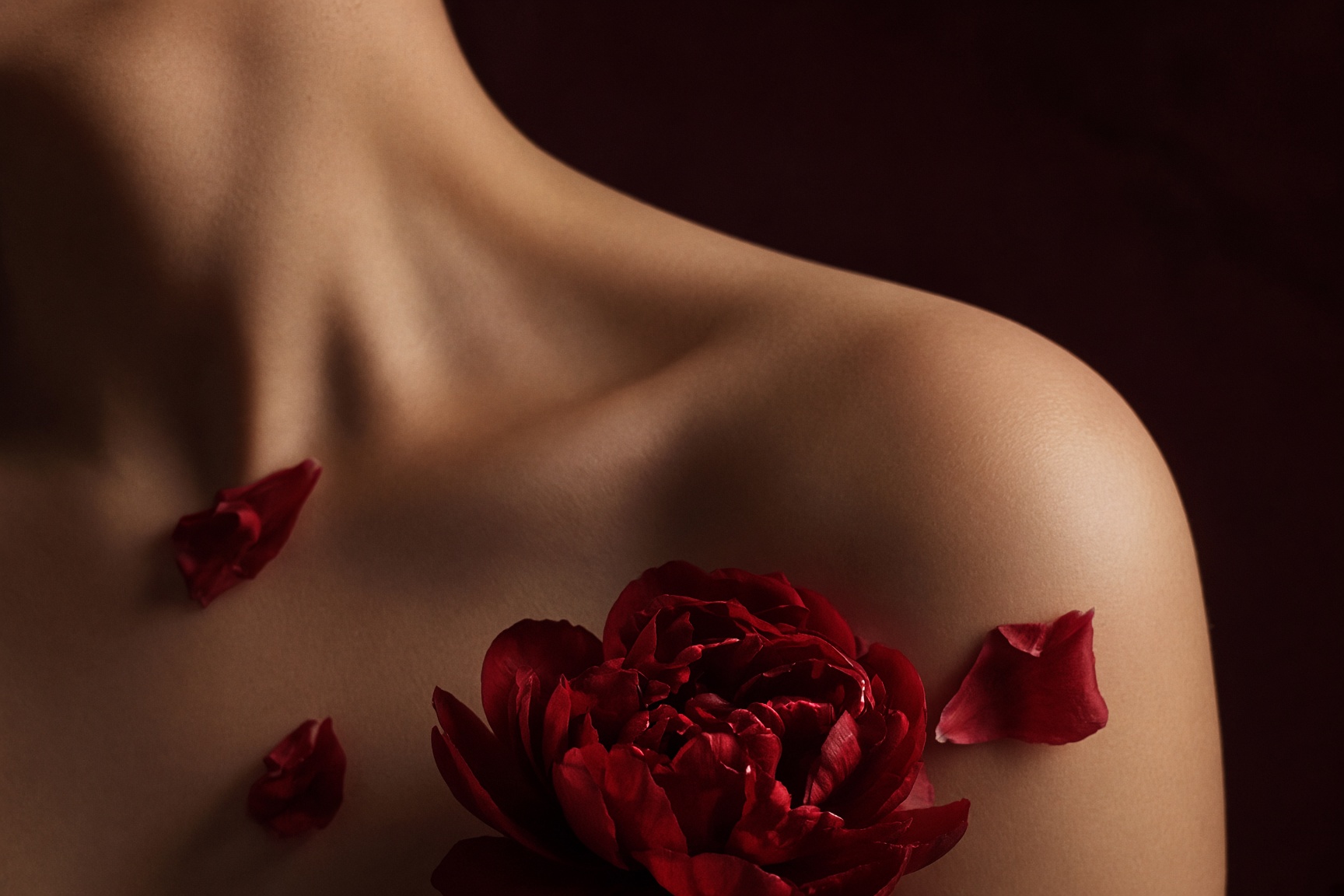 A shoulder with a dark peony, cropped above the face